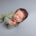 baby boy in a green romper on a grey blanket fast asleep by Hull newborn photographer