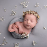 baby girl wrapped up and lying on a grey background by Hull newborn photographer