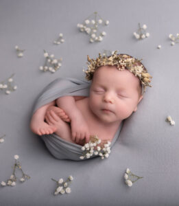 baby girl wrapped up and lying on a grey background by Hull newborn photographer