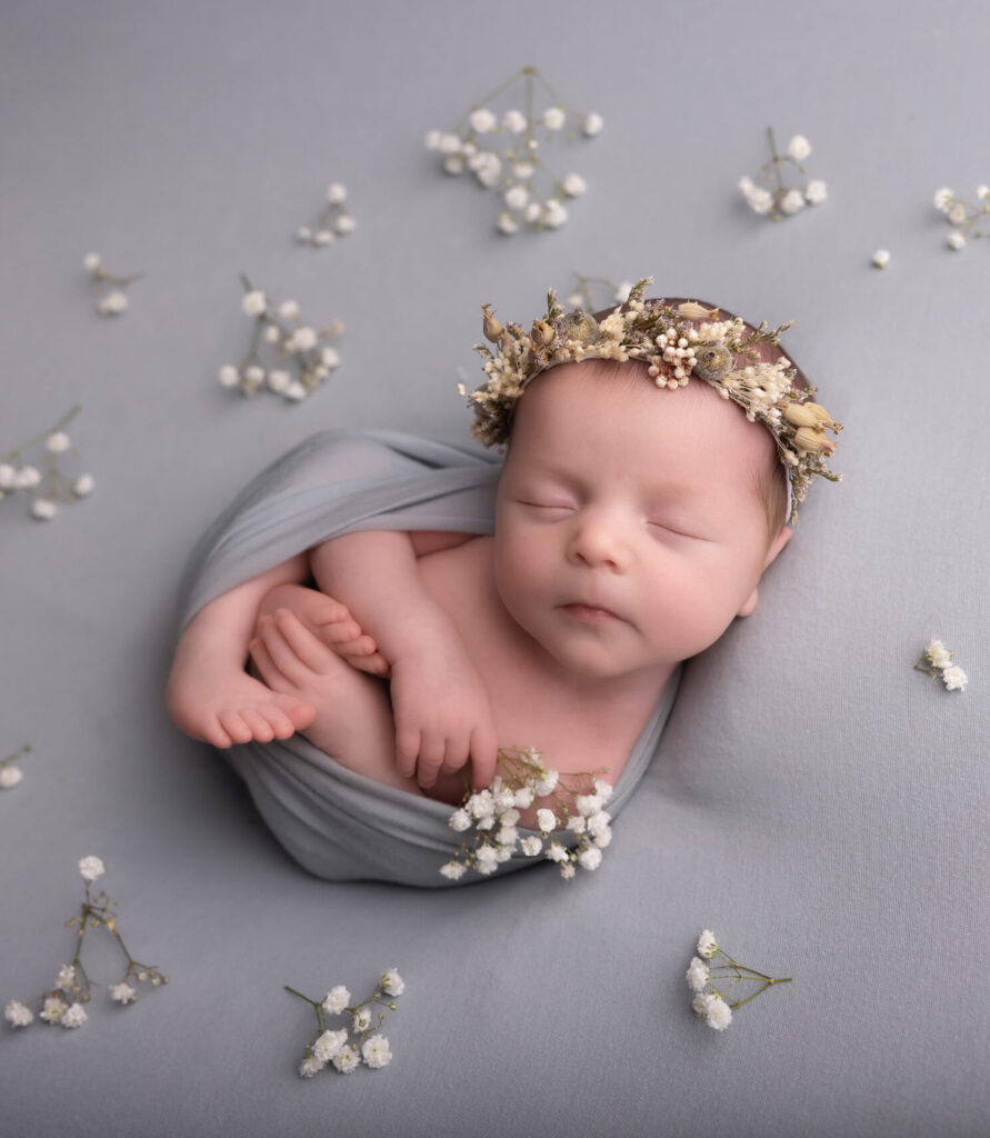 baby girl wrapped up and lying on a grey background by Hull newborn photographer