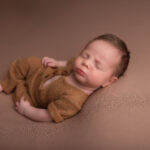 baby boy in a brown romper asleep on his back on a brown blanket by Hull newborn photographer