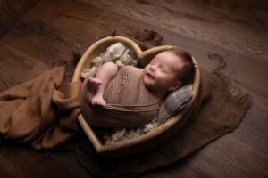 Wrapped newborn posed safely in a cosy neutral setup at Kerry Jones Photography studio.