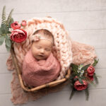 baby girl in pink wrap inside a wicker basket by Hull newborn photographer