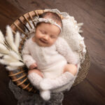 baby girl in a white knitted romper in a basket by Hull newborn photographer