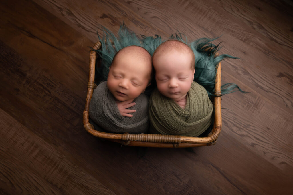 newborn twins swaddles together in a basket at their newborn photoshoot