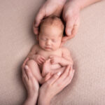 baby asleep in mym and dad's hands on a cream blanket by Hull newborn photographer