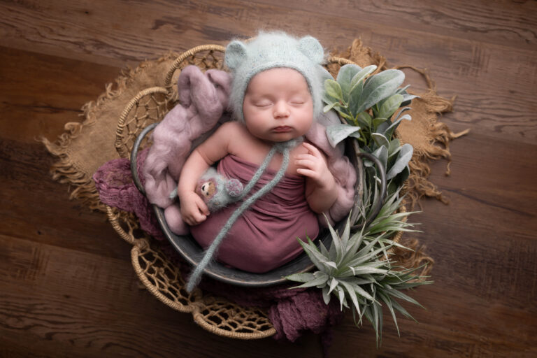 Professional newborn photographer gently posing a sleeping baby with a baby-led approach to newborn photography