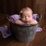 baby gurl asleep with her head on hnds in a metal bucket by Hull newborn photographer