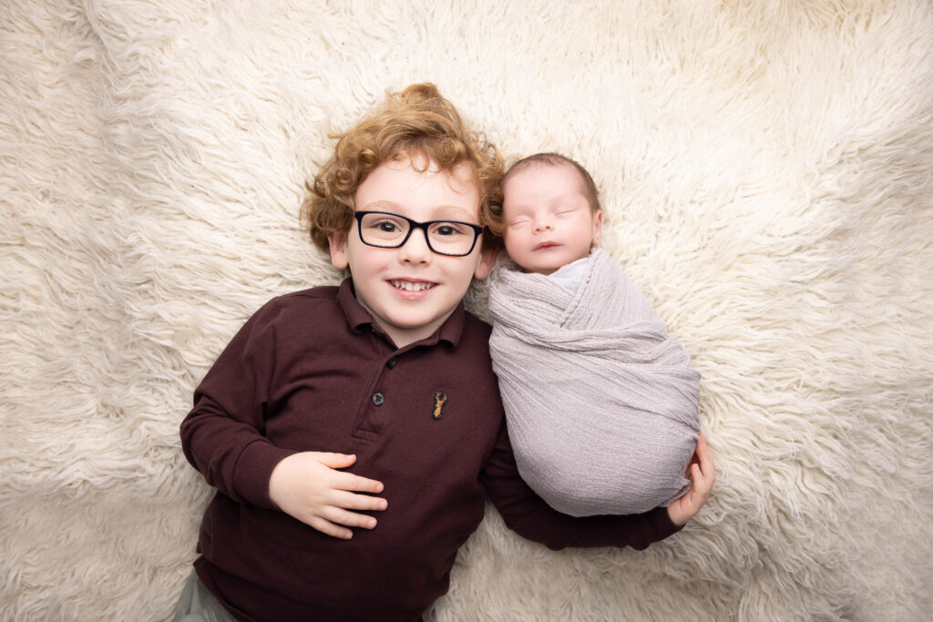 baby boy with older brother lying down by Hull newborn photographer