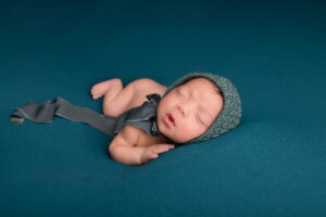 sleeping baby wearing aa bonnet lying on a teal coloured blanket